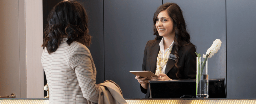manager using hotel tech stack at reception desk